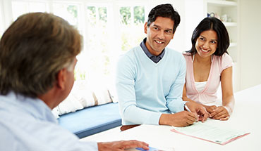A couple signing papers with an advisor