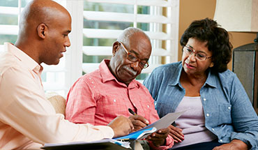 A senior couple reviewing paperwork with a financial advisor